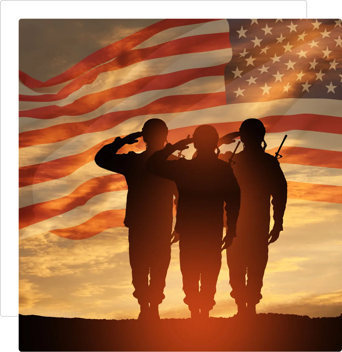 Three soldiers saluting the American flag at sunset.