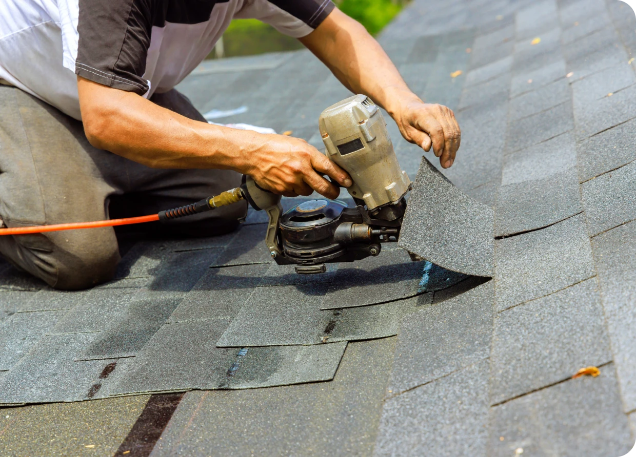 Roofer using nail gun on shingles